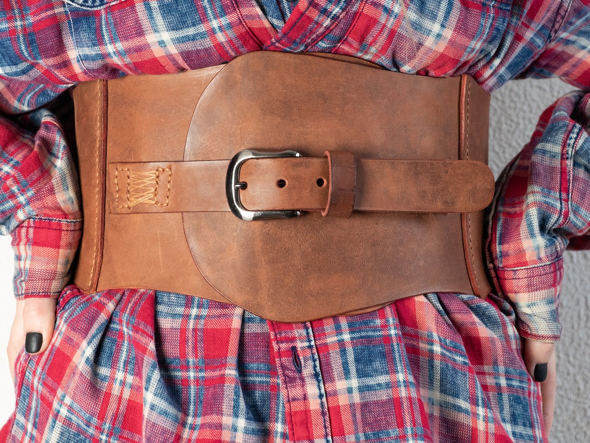 A woman in a red shirt and brown leather corset