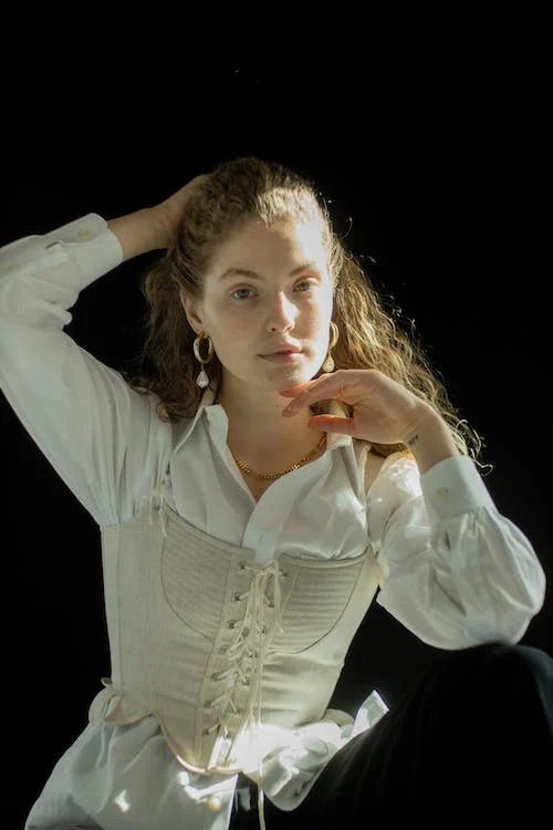 A woman in white polo shirt and white corset