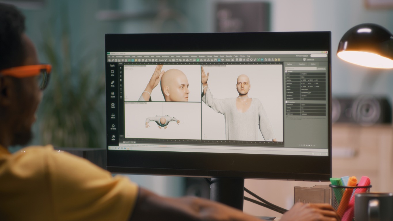 Black guy creating a 3D model of a bald human for a movie or video game on a computer during work in home office