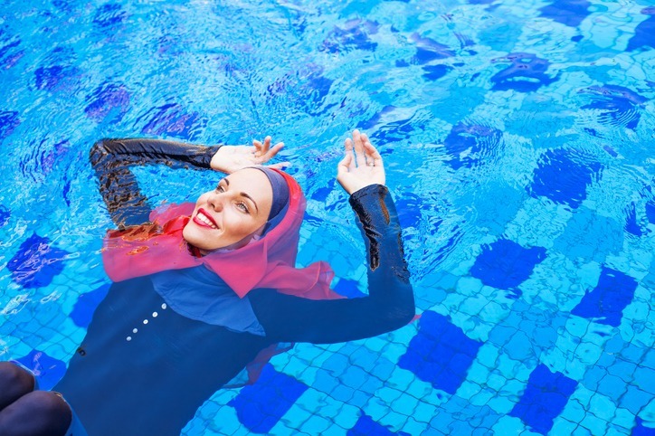 muslim caucasian woman swimming in a swimming pool