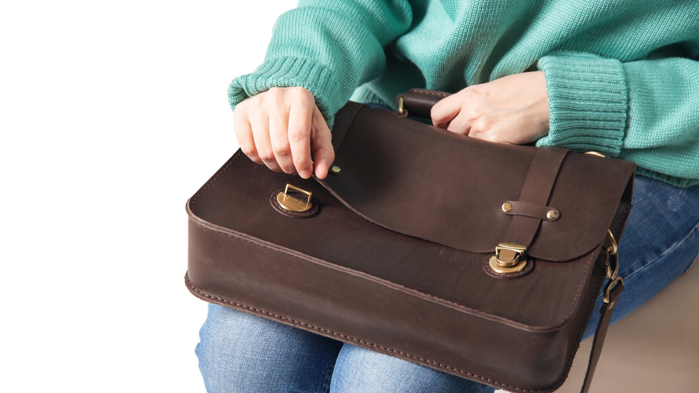 a woman sitting at the park bench beside her briefcase